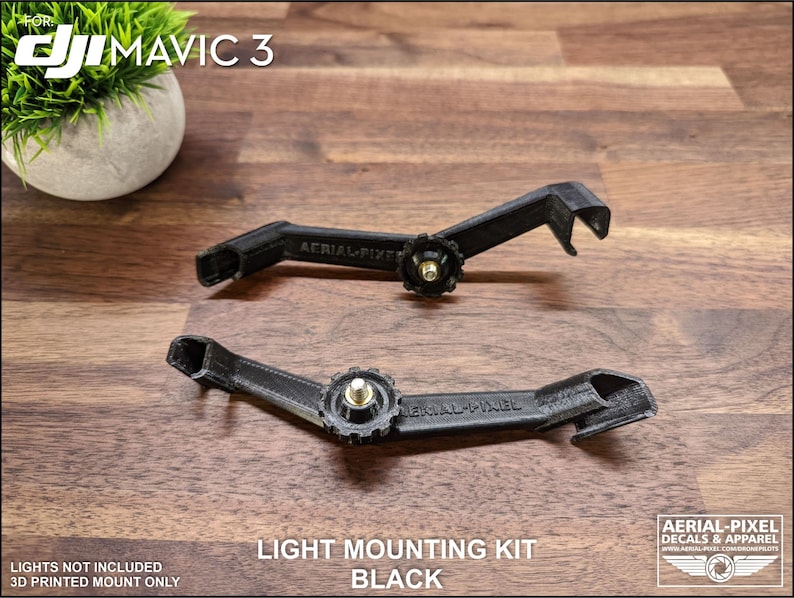 K&ouml;nnte beinhalten: Zwei schwarze Lichtmontages&auml;tze f&uuml;r DJI Mavic 3 Drohnen. Die S&auml;tze sind 3D-gedruckt und verf&uuml;gen &uuml;ber einen zentralen Einstellknopf und Befestigungspunkte. Der Text "LIGHT MOUNTING KIT BLACK" ist sichtbar.