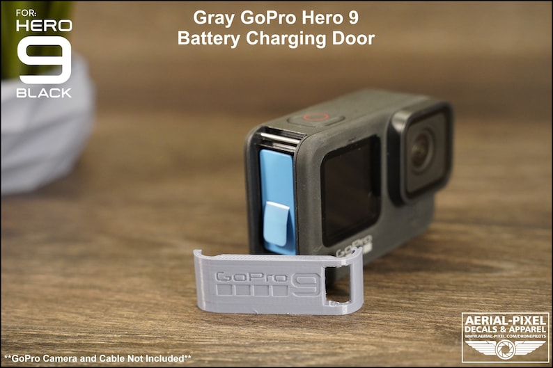 May include: Gray GoPro Hero 9 battery charging door replacement. The door is made of gray plastic and has the GoPro logo and the number 9 printed on it. The door is shown next to a black GoPro Hero 9 camera.