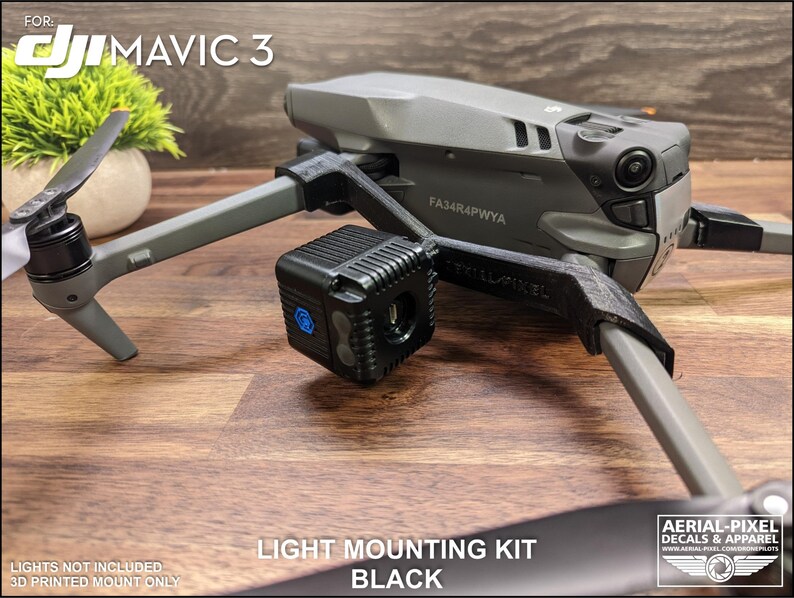 K&ouml;nnte beinhalten: Schwarzes Lichtmontage-Kit f&uuml;r eine DJI Mavic 3 Drohne. Das Kit enth&auml;lt eine 3D-gedruckte Halterung und ist f&uuml;r die Aufnahme von Lichtern konzipiert. Die Drohne ist grau mit schwarzen Propellern. Der Text "LIGHT MOUNTING KIT BLACK" ist sichtbar.