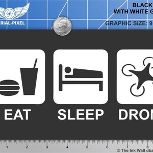 May include: Black t-shirt with a white graphic that says "Eat, Sleep, Drone". The graphic is 9.0 inches by 3.5 inches.