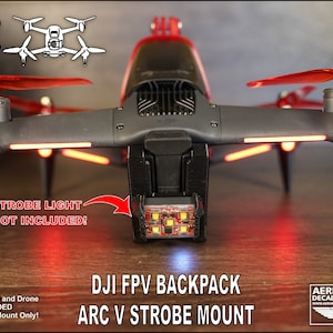 Può includere: Un supporto per luce stroboscopica stampato in 3D, progettato per adattarsi al drone DJI FPV. Il supporto è nero e ha una luce stroboscopica rossa attaccata ad esso. Il testo "DJI FPV BACKPACK ARC V STROBE MOUNT" è stampato nella parte inferiore dell'immagine.