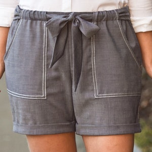 May include: Gray linen shorts with a white drawstring tie and white topstitching. The shorts have two front pockets.