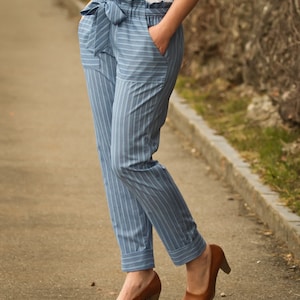 May include: Blue and white striped pants with a wide waistband and a bow tie. The pants have a cuffed hem and are worn with brown heeled shoes.