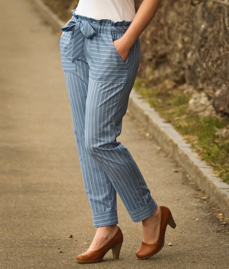 May include: Blue and white striped pants with a wide waistband and a bow tie. The pants have a cuffed hem and are worn with brown heeled shoes.