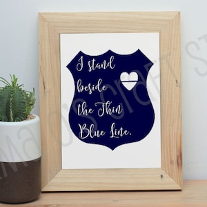 Peut inclure: Une impression encadrée avec un design de badge de police bleu et le texte "Je me tiens aux côtés de la ligne bleue mince."