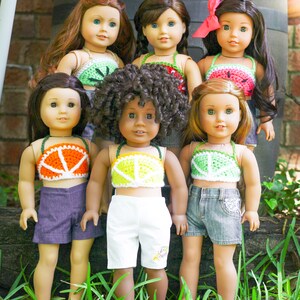 May include: Six dolls wearing crocheted fruit-themed tops. The tops are watermelon, orange, lime, and kiwi. The dolls are wearing various shorts and skirts.