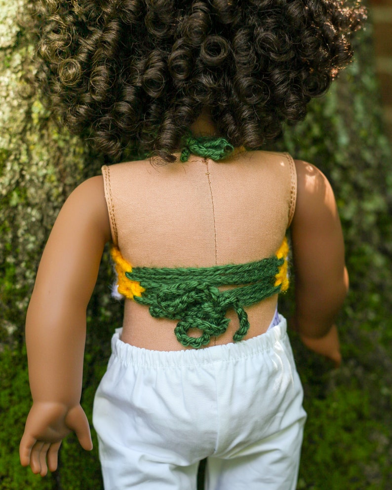 May include: A doll wearing a green and yellow crocheted halter top with a white skirt.