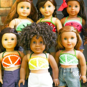 May include: Six dolls wearing crocheted fruit-themed tops. The tops are made with different colors of yarn and feature various fruits, including watermelon, lemons, and oranges. The dolls are wearing different colored shorts and have different hairstyles.
