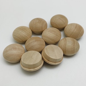 May include: A group of ten round wooden knobs in a light brown color. The knobs are arranged in a loose circle on a white surface.