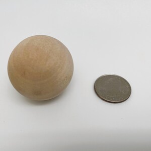 May include: A light brown wooden ball, approximately the size of a US quarter.