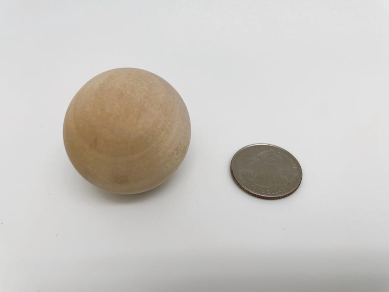 May include: A light brown wooden ball, approximately the size of a US quarter.