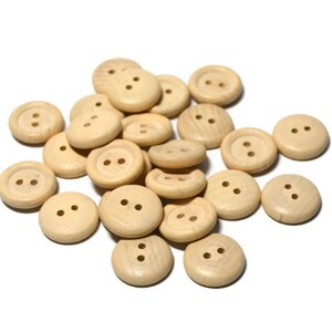 May include: A pile of natural wood buttons with two holes each. The buttons are round and have a smooth, slightly textured surface.