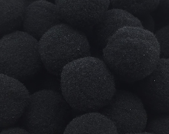 May include: A close-up image of a pile of black pom-poms. The pom-poms are soft and fluffy, and they are perfect for adding a touch of whimsy to any craft project.