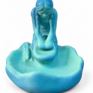 Könnte beinhalten: Eine Keramikschale mit einer knienden Figur, die Wäsche in einem Becken wäscht. Das Objekt ist in einem Farbverlauf aus Blau- und Türkistönen gehalten und weist eine sichtbare Craquelé-Glasur auf der gesamten Oberfläche des Stücks auf.