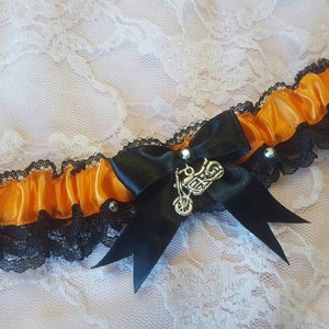 May include: Orange and black garter with a silver motorcycle charm and a black satin bow.