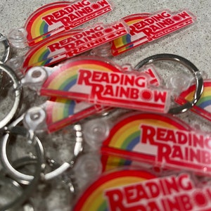 May include: A close-up of a pile of colorful keychains with a rainbow design and the text "Reading Rainbow".
