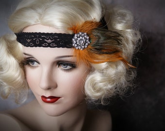 May include: A black lace headband featuring a circular silver-toned brooch with clear rhinestones and orange and brown feathers. The accessory is worn on a blonde mannequin head with curled hair, red lipstick, and blue eyes, creating a distinct look.