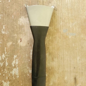 May include: A putty knife with a black handle and a light gray blade. The tool is designed for applying or removing putty, caulk, or other similar materials. The handle is ergonomically shaped for a comfortable grip.