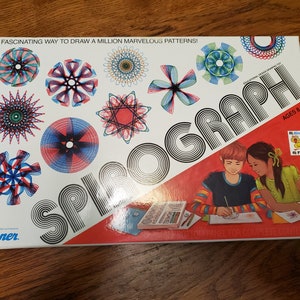 May include: Spirograph drawing toy box with colourful geometric designs. The box features the word "Spirograph" in large letters, illustrations of children, and the text "Ages 8+". The box is white with red accents.