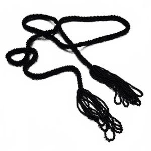 May include: A long, black beaded necklace featuring a continuous strand of small, uniform black beads. The necklace is designed with two decorative, dangling beaded tassels at the ends, creating a fluid and flexible accessory with a dark, monochromatic appearance.