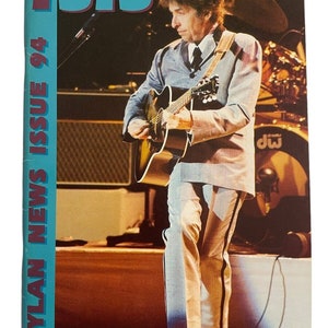 May include: A magazine cover featuring a photo of Bob Dylan playing a guitar. The magazine is titled "ISIS Dylan News Issue 94".