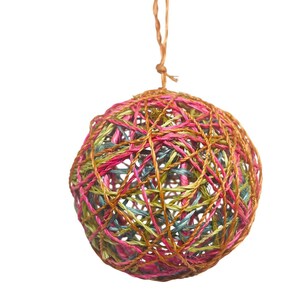 May include: A colorful, spherical ornament made of interwoven strands of pink, green, blue, and brown fibers. A brown string is attached at the top for hanging. The decorative ball has a textured, woven appearance and is set against a white background.