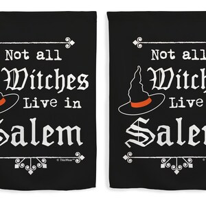 May include: Two black decorative flags with white text and a witch hat graphic. The text reads "Not all Witches Live in Salem". The witch hat is black with an orange band. Decorative elements are at the top and bottom.