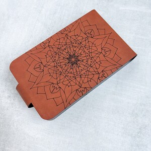 May include: A brown leather notebook with a black mandala design on the cover.