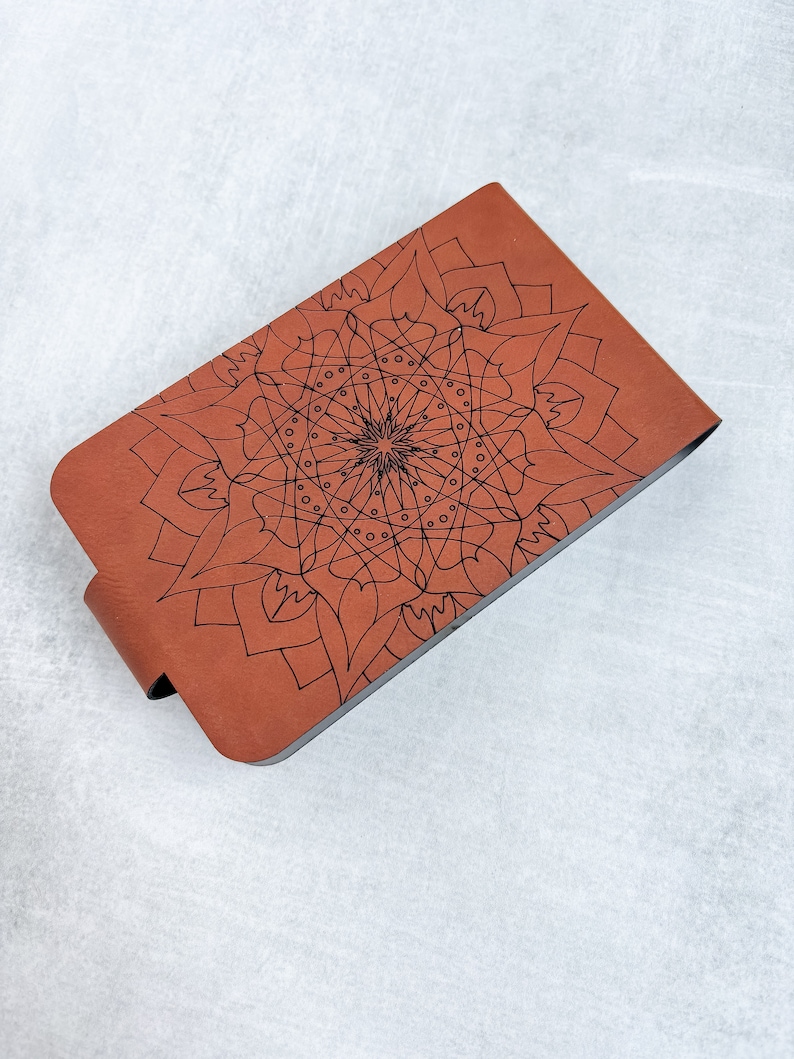 May include: A brown leather notebook with a black mandala design on the cover.