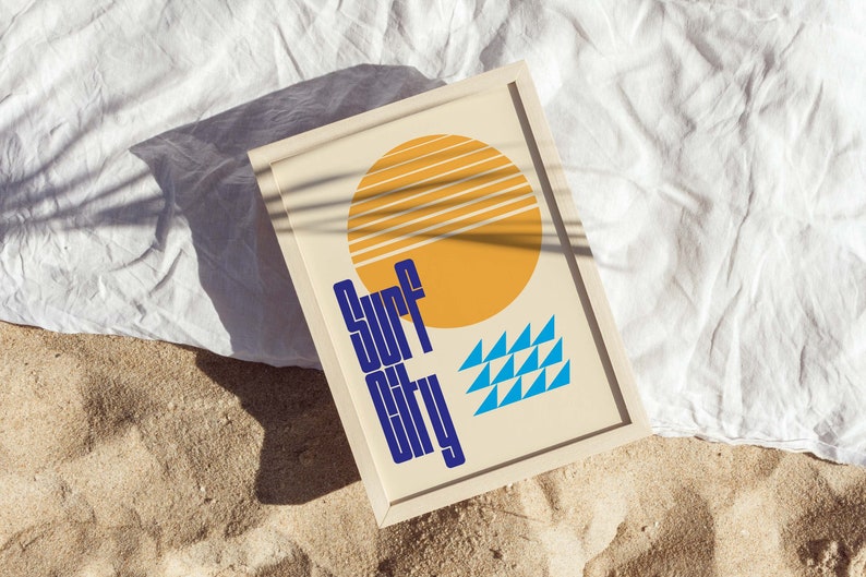 Puede incluir: Una impresi&oacute;n enmarcada con un dise&ntilde;o retro que presenta un sol amarillo con rayas azules y blancas, tri&aacute;ngulos azules y el texto "Surf City" en azul.