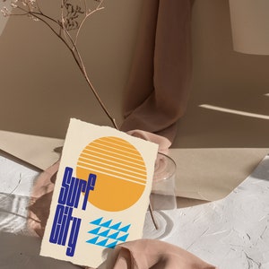 Puede incluir: Un fondo texturizado beige y blanco con una tela marr&oacute;n drapeada sobre una superficie blanca. Un sol amarillo con rayas naranjas y un patr&oacute;n geom&eacute;trico azul y blanco est&aacute;n en una tarjeta crema con el texto "Surf City" en azul.