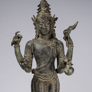 May include: A four-armed bronze statue of a deity with a crown and elaborate jewellery. The statue is standing on a lotus base and has a green patina.