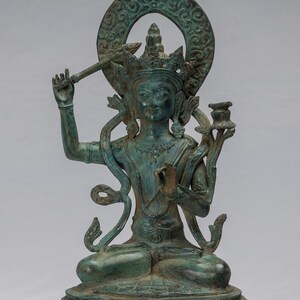 May include: A green bronze statue of a deity sitting in a meditative pose. The deity has a crown and is adorned with jewelry. The statue is on a base with intricate carvings.