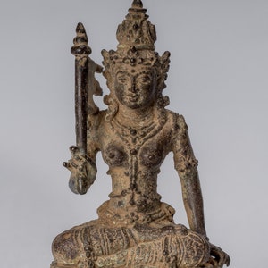 Puede incluir: Una estatua de bronce de una deidad femenina sentada con una corona y un bastón. La estatua está intrincadamente detallada y tiene una pátina desgastada.