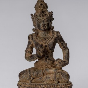 Op de afbeelding: Een klein bronzen beeld van een zittend vrouwelijk figuur met een kroon en uitgebreide sieraden. Het beeld is in een meditatieve houding met de handen voor de borst gevouwen. De figuur zit op een lotusbloembasis.