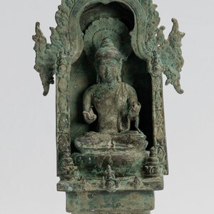 May include: A weathered bronze statue of a seated Buddha figure within an ornate archway. The statue is mounted on a tiered base, with intricate details and a verdigris patina. The overall design suggests a religious or decorative item.