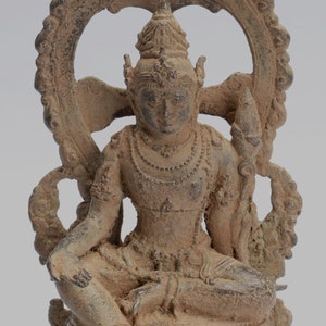 May include: A bronze statue of a seated deity with a halo and intricate details. The statue is in a meditative pose with hands clasped in front of the chest. The deity is adorned with jewelry and a crown.