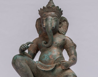 May include: A green bronze statue of Ganesha, the Hindu god of wisdom and prosperity, sitting with his right leg bent and his left leg extended. He is wearing a crown and has an elephant head with a trunk that is curled up. The statue is on a square base.