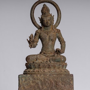 Puede incluir: Una estatua de bronce de una deidad sentada con un halo, que lleva una corona y joyas elaboradas. La estatua está sobre una base cuadrada con un diseño de flor de loto.