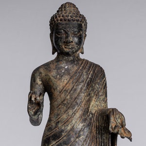 Op de afbeelding: Een bronzen beeld van een zittende Boeddha met een serene uitdrukking. Het beeld is in een meditatieve houding met de handen in de meditatiehouding. Het beeld staat op een vierkante basis met ingewikkelde houtsnijwerk.