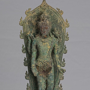 May include: A green bronze statue of a standing deity with a flame-like halo. The deity is holding a staff in their right hand and a bowl in their left hand. The statue is standing on a base with a seated figure.