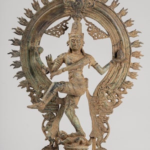 Peut inclure: Une sculpture en bronze du dieu hindou Shiva dans la pose de Nataraja, dansant sur un démon. Shiva est représenté avec quatre bras, tenant un tambour, un feu, un geste de la main et un crâne. Il est entouré d'une auréole circulaire de flammes.