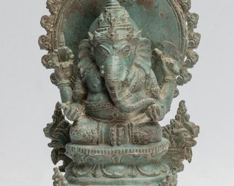 May include: A green bronze statue of Ganesha, the Hindu god of wisdom and prosperity, seated on a throne with a halo behind him. The statue is intricately detailed and has a weathered patina.
