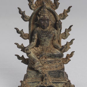 Könnte beinhalten: Eine Bronzestatue einer Gottheit, die auf einem Thron mit einem flammenartigen Heiligenschein sitzt. Die Statue ist in sitzender Position mit mehreren Armen und Händen. Die Gottheit trägt eine Krone und verzierte Schmuckstücke. Die Statue ist dunkelgrün mit einer Patina-Oberfläche.
