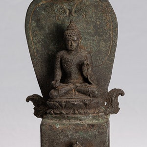 Pode incluir: Uma estátua de bronze de um Buda sentado, com um capô de cobra atrás da figura. A estátua está sobre uma base quadrada com um desenho de roda.