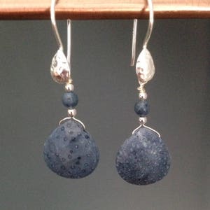 May include: A pair of silver dangle earrings with dark blue gemstone beads and textured silver teardrop charms.
