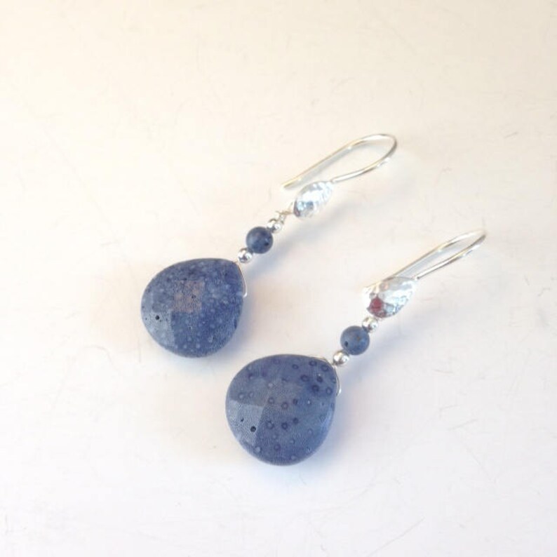 May include: A pair of silver dangle earrings with blue stone drops. The stones have a textured surface.