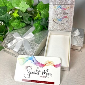 Pode incluir: Uma caixa de presente prateada com uma fita de cetim branca e um cart&atilde;o branco com o texto "Scarlet Mare Studio" e "Artisan Jewelry - Bringing Color to Life".