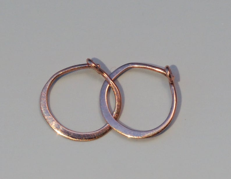 May include: A pair of small, simple, gold hoop earrings. The hoops are smooth and have a slightly hammered texture.