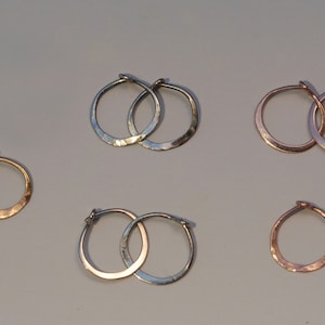 May include: Set of six hammered hoop earrings in silver, gold, and rose gold. The earrings are all different sizes.